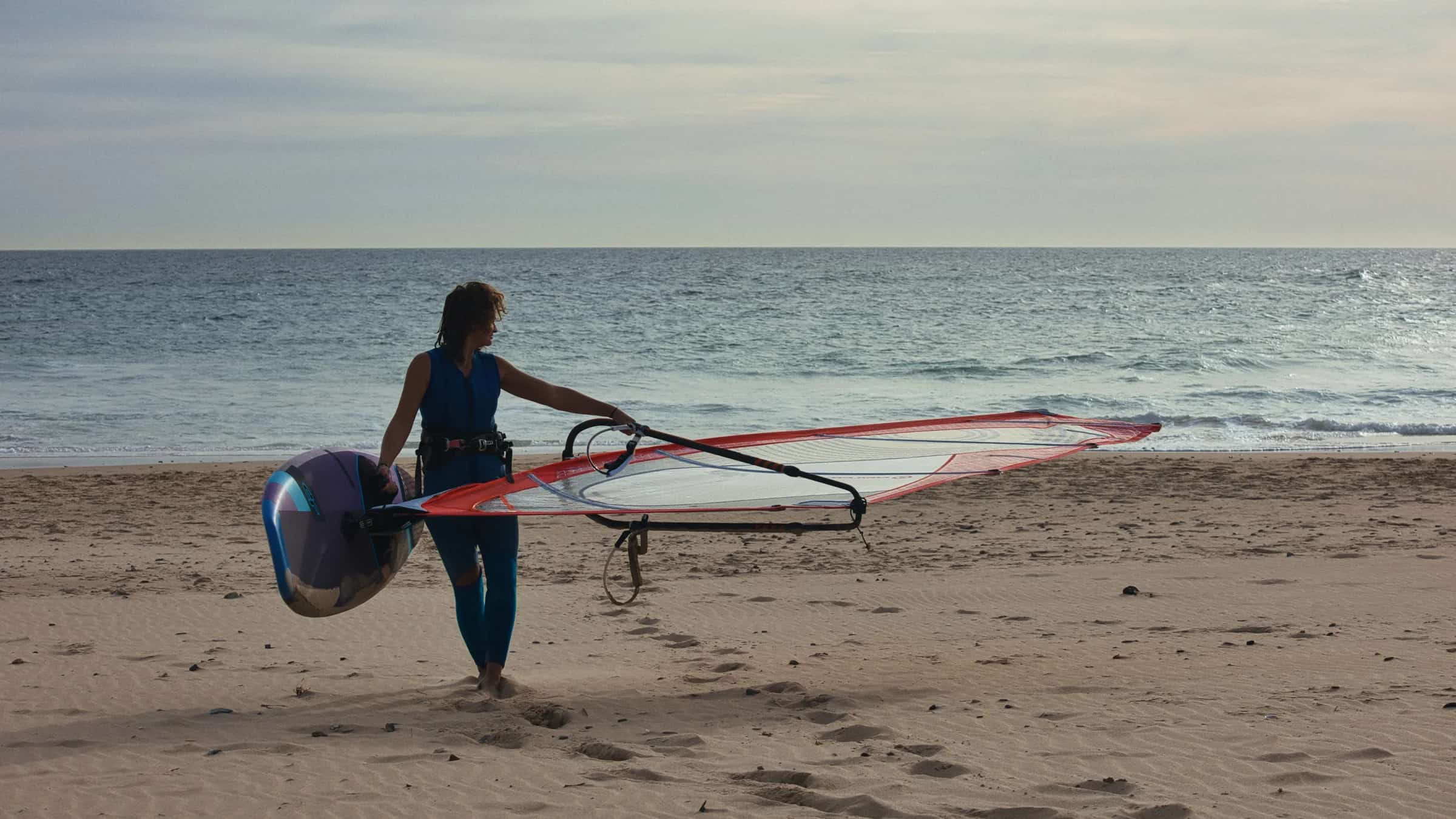 Windsurf ekipmanıyla kıyıya hazırlanan sporcu