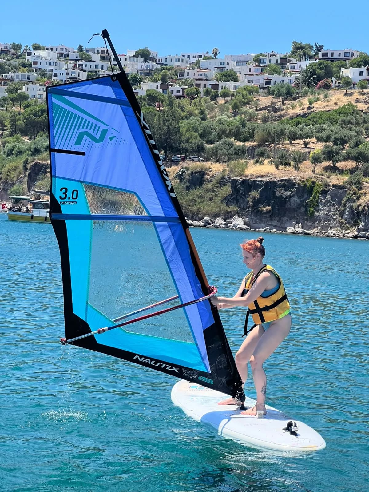 Akyarlar koyunda küçük yelkenle windsurf yapan katılımcı