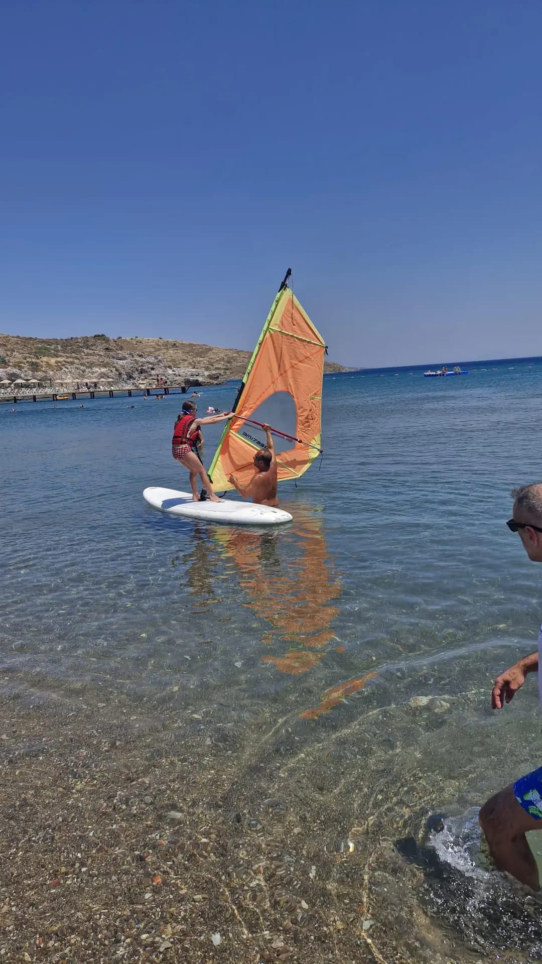 Bodrum kıyısında yelkenli board üzerinde çalışan katılımcı ve eğitmen
