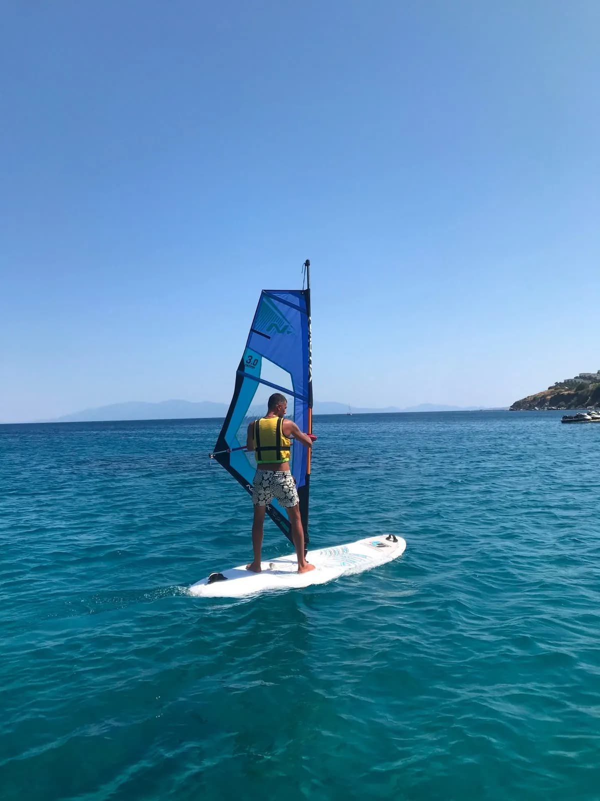 Bodrum koyunda kıyıya kontrollü şekilde dönen windsurf katılımcısı