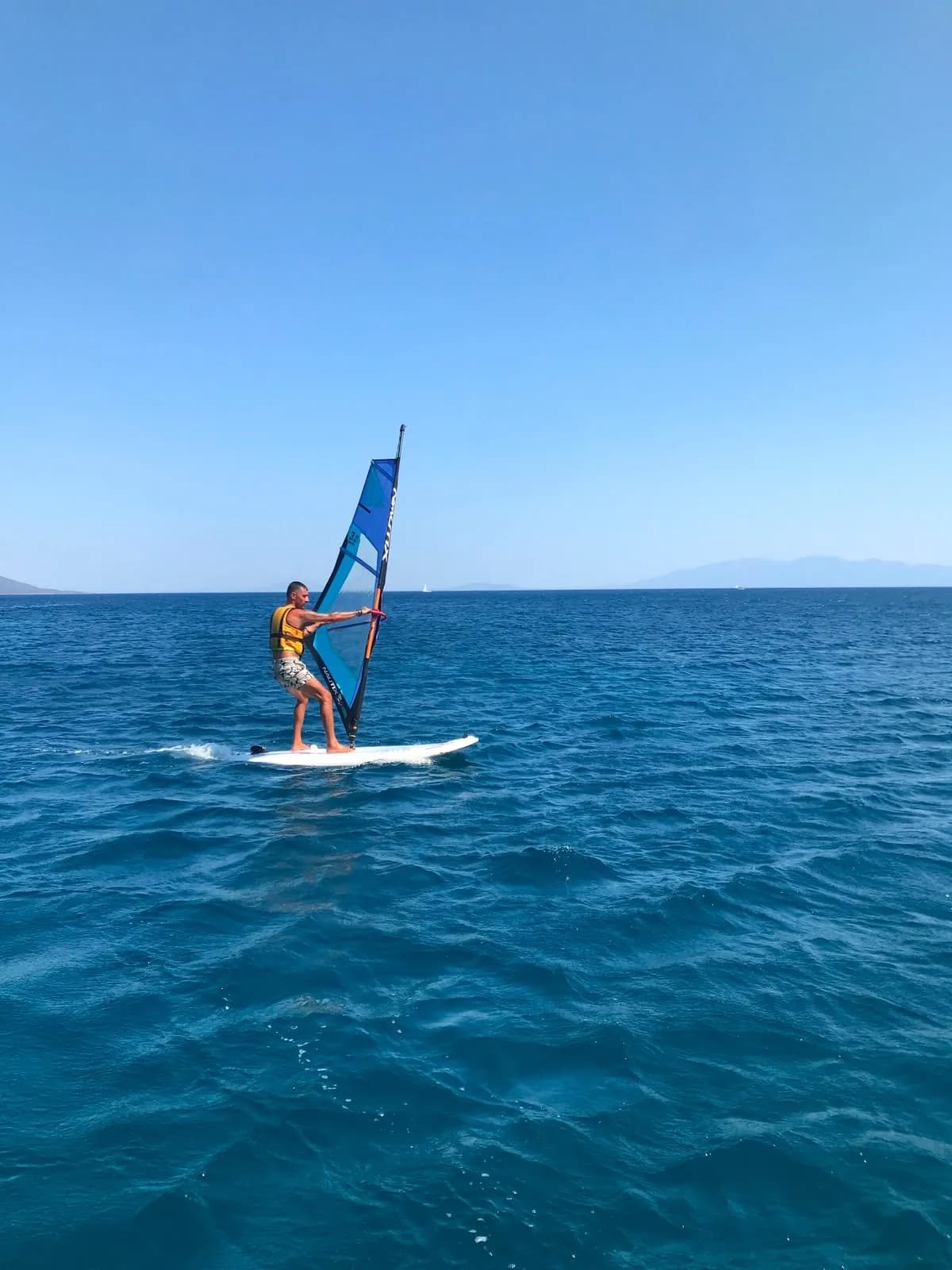 Açık suda windsurf tahtası üzerinde temel kontrol çalışan katılımcı